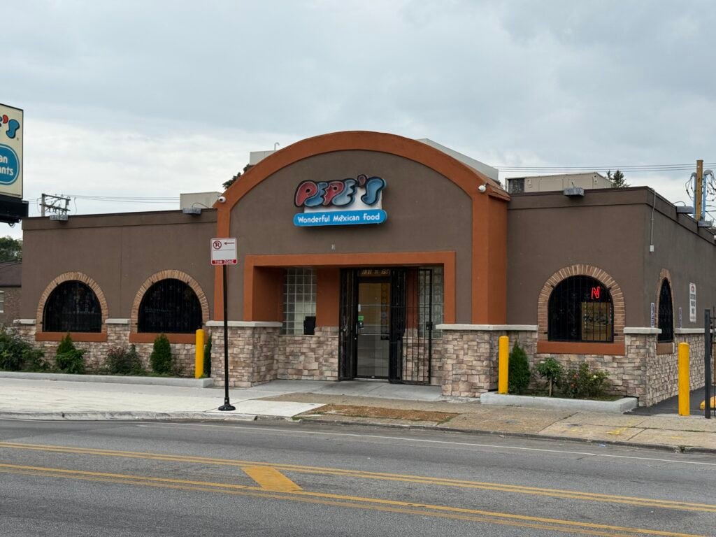 Exterior of Pepe’s Mexican Restaurants & Cantina with brick wall, colorful logo sign, and neon OPEN light in the window.